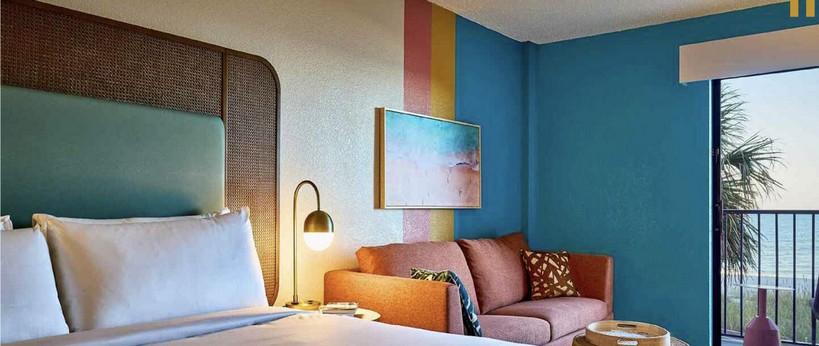 Voco the Shelby guestroom with bold teal wall and colorful sofa